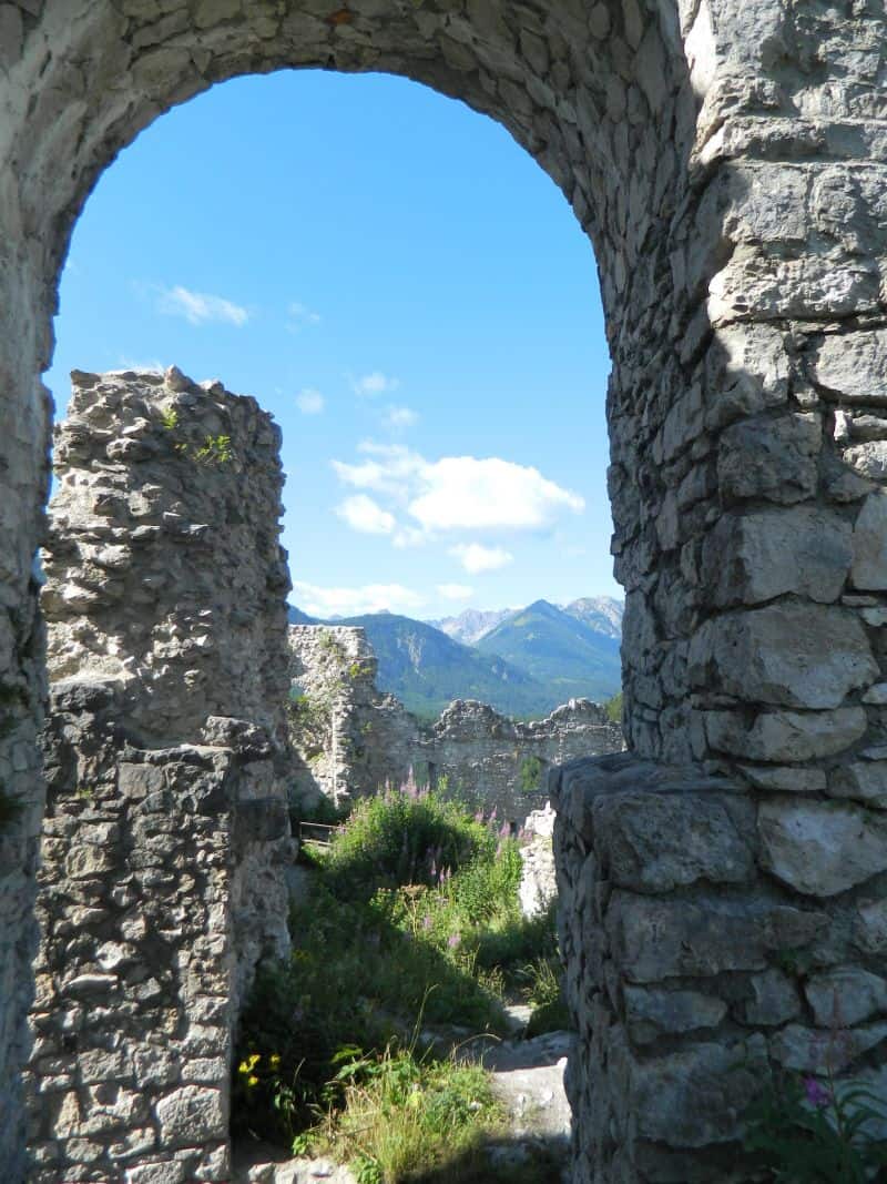 View through archway at Castle Ruin near Reutte, Germany. Inspiration for a setting in Murder in Black Tie, Book 4 in the High Society Lady Detective series by Sara Rosett.